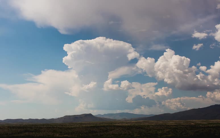 Clouds move along a mountain range in the distance
