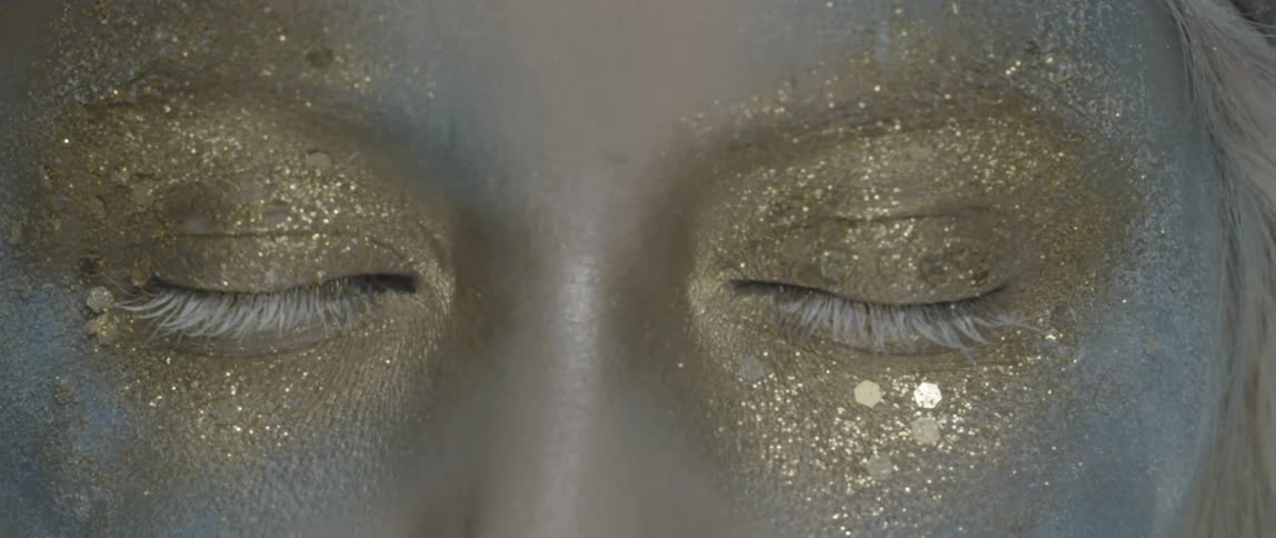 A woman wearing glittery make up and blinking