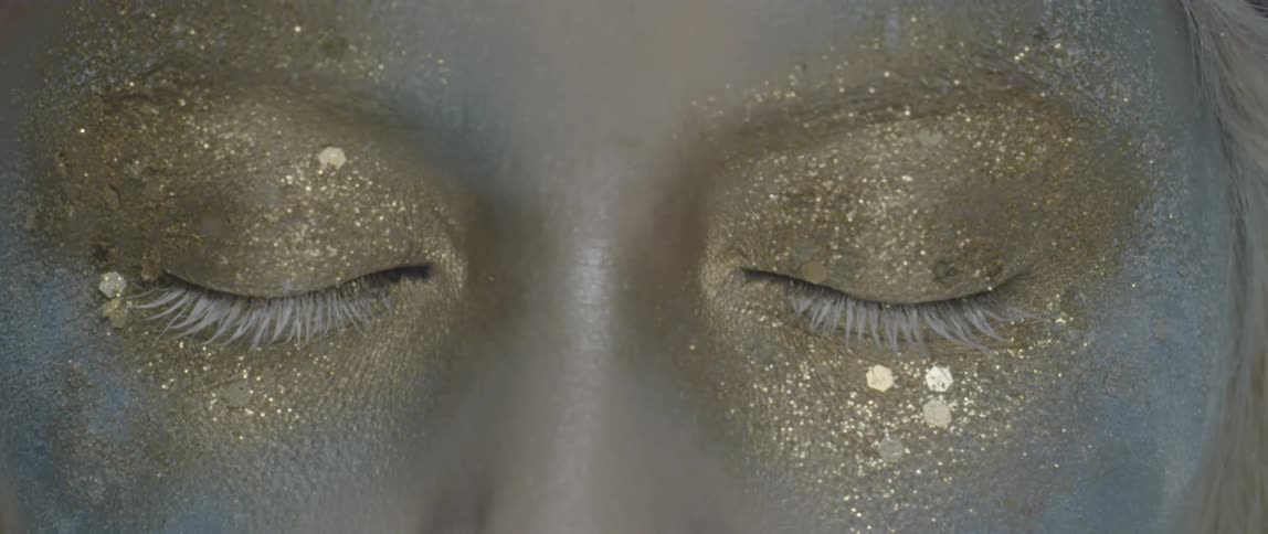 A person has gold glitter all of their eyes