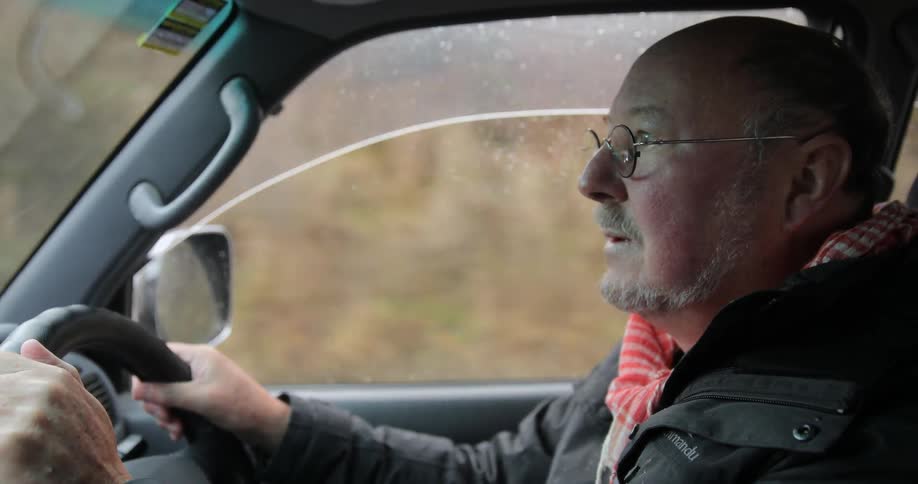 A man is driving a car and adjusting the sunroof