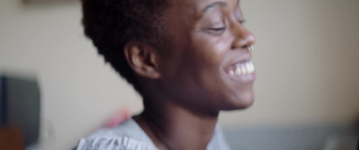 A woman smiling and talking into a mic with a pop guard