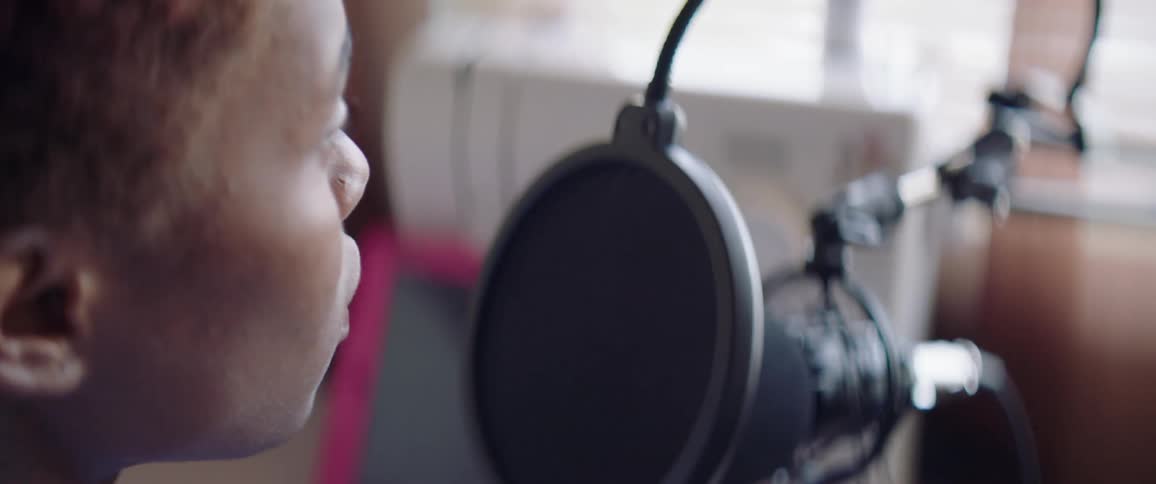 Woman sits talking into professional grade microphone