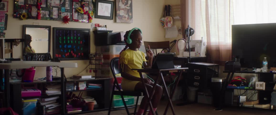 A young girl in a yellow dress sings while listening to headphones