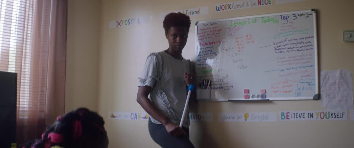 A student writes as a teacher stands