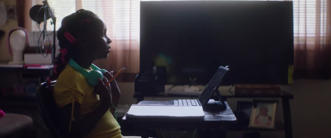 A woman standing next to a white board talking to a girl sitting at a desk with a laptop