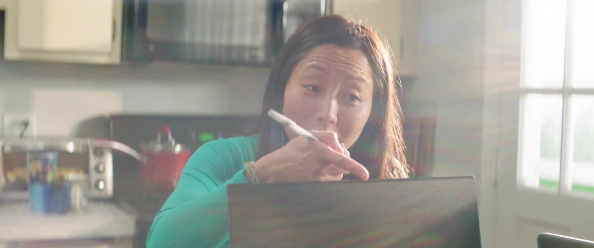 A group of women talk and work on laptops in a kitchen