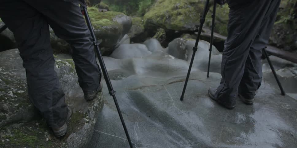 People are standing near their tripods set up on rocks