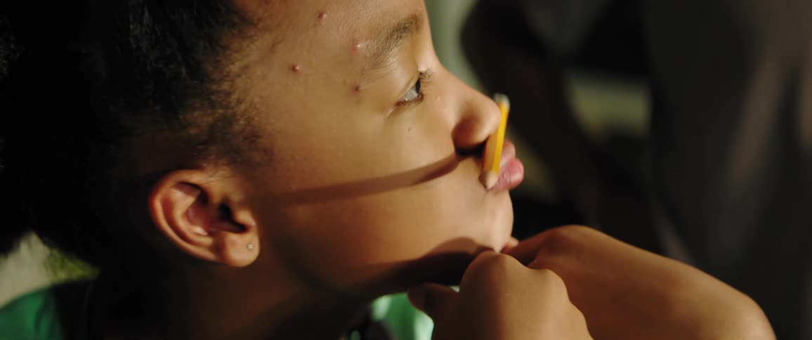 Close up of a girls face balancing a pencil between her nose and lips