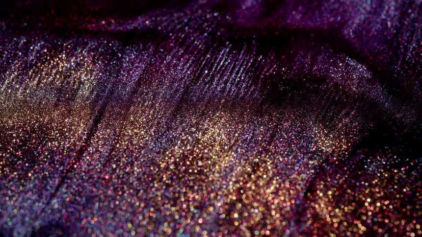 Purple mas with glittering particles stretches and expands as it flows
