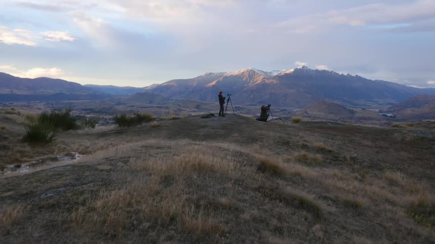 Two people are taking photographs on a hilly valley