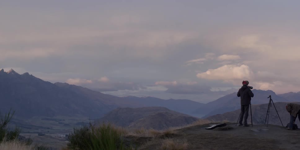 Two photographers taking pictures of mountains on a cloudy day