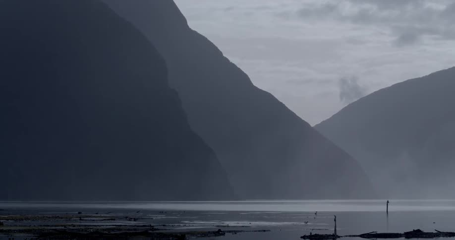 The shoreline of a mountain lake on a cloudy evening
