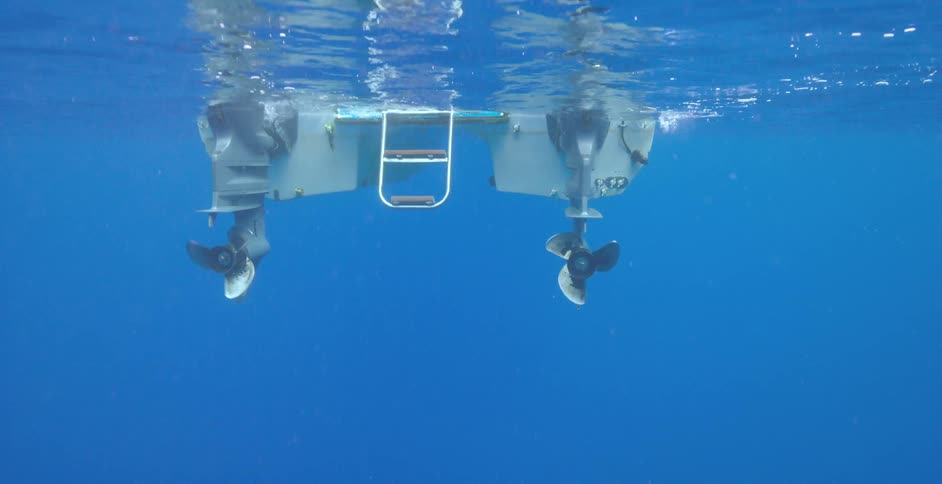 Propellers on a small boat spin in the water