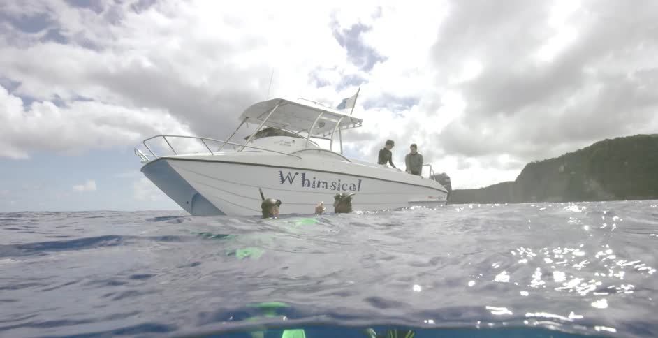 Two people swim in the water near a boat