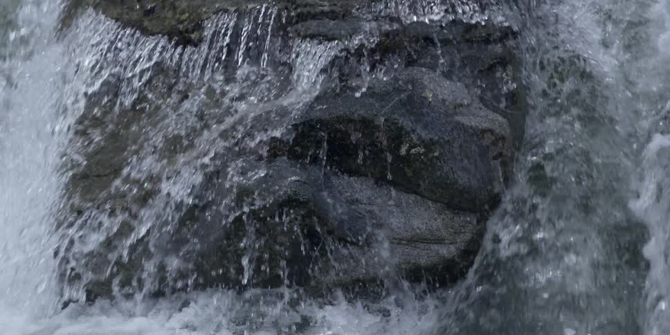 Water falls down a large, bumpy rock