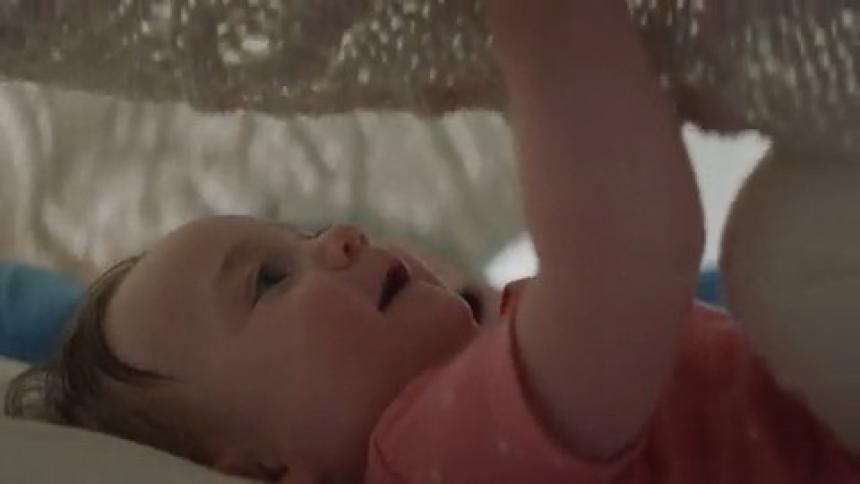 A girl and her brother play under a blanket by kicking it