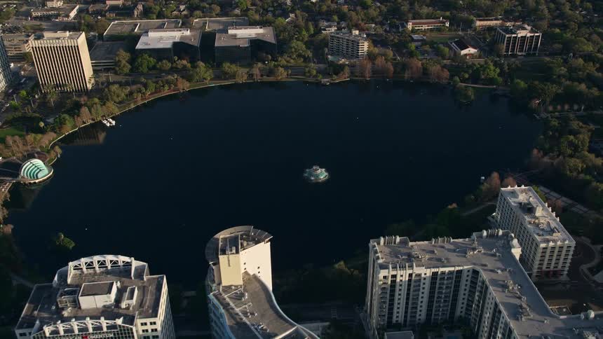 Aerial footage of Lake Eola in downtown Orlando at sunrise over the city skyline and man-made lake