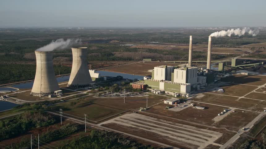 An aerial view of the Stanton Energy Center power plant in Orlando Florida at sunrise showcasing the plants smokestacks at dawn
