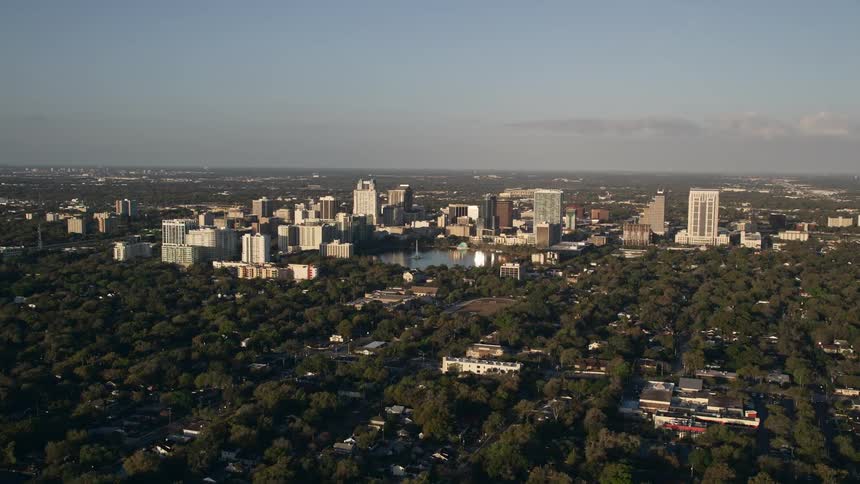 Aerial of Downtown Orlando at sunrise showcasing the metropolis waterfront properties and the clear blue skies during spring or summer