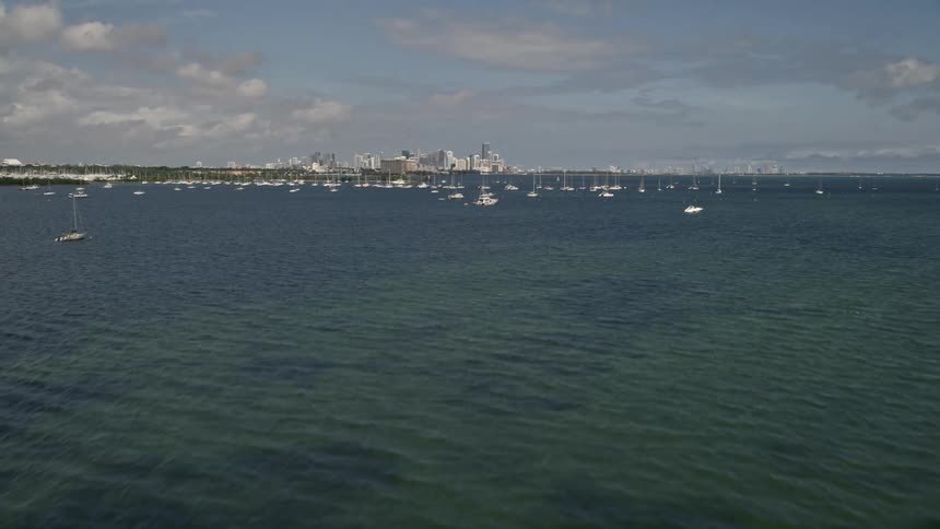 Aerial footage of sailboats on the ocean and Downtown Miami skyline is revealed after a flyover of Biscayne Bay in Florida
