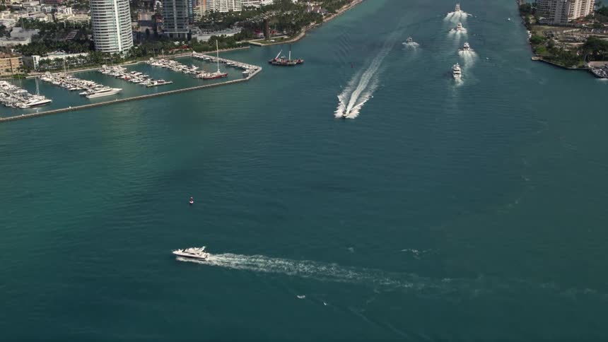 Aerial footage tilting up from Government Cut reveals South Beach skyscrapers and ferries on a partly cloudy day in Miami Florida
