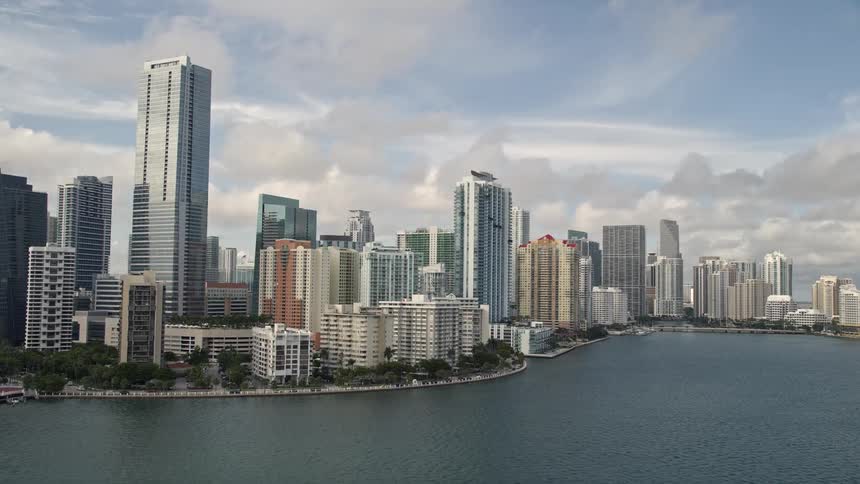 The camera tilts up to reveal the skyline of Downtown Miami overlooking the ocean in Southern Florida capturing the towering high-rises and luxurious hotels lining the coastline