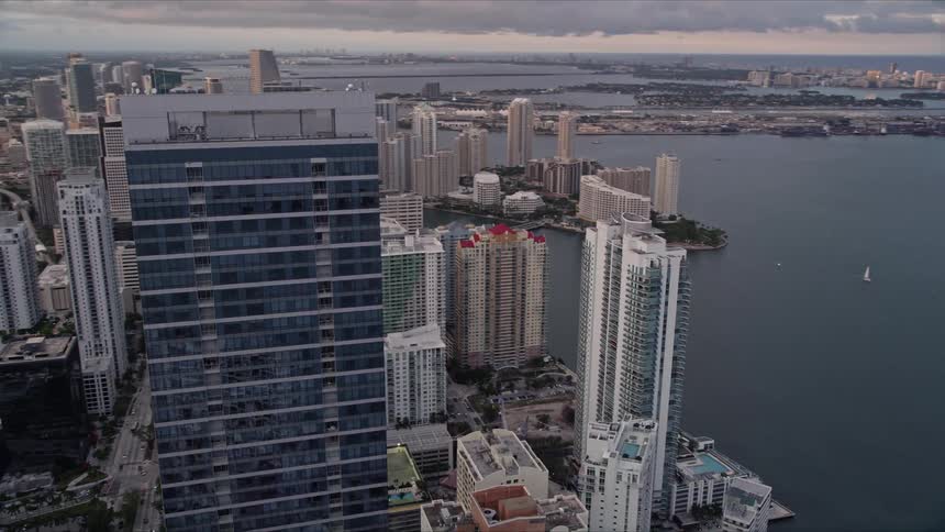 Aerial footage of Downtown Miami at sunset showcasing the Four Seasons Hotel and waterfront skyscrapers amidst the metropolis of the city
