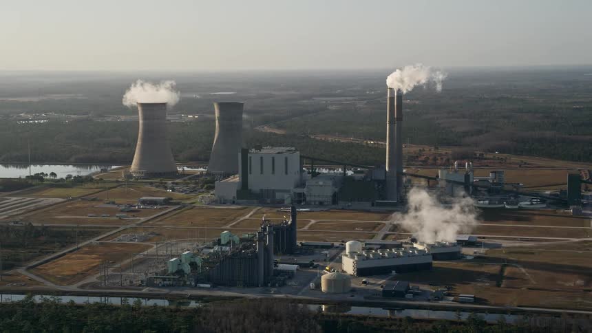 Approaching Stanton Energy Center power plant at sunrise in Orlando smoke stacks and industrial structures rise between waterways