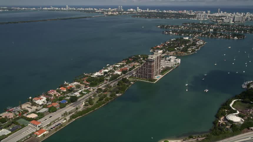 Aerial view of waterfront homes and apartment buildings on the Venetian Islands in Miami Florida with partly cloudy skies and a tilt up shot