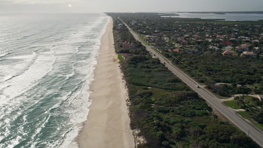 Aerial flyover of Melbourne Beachs sandy shoreline and coastal community in Florida showcasing the scenic coastline and apartment buildings