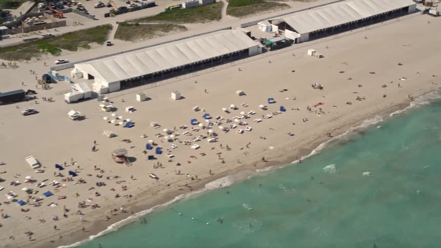 Sunbathers enjoying the crowded South Beach Florida shorelines on a sunny day in this 5K aerial stock footage