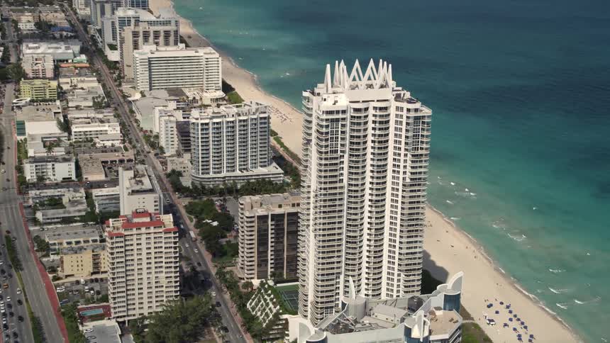 Aerial footage of the beachfront condos and hotels in Miami Beach Florida with people relaxing on the beach