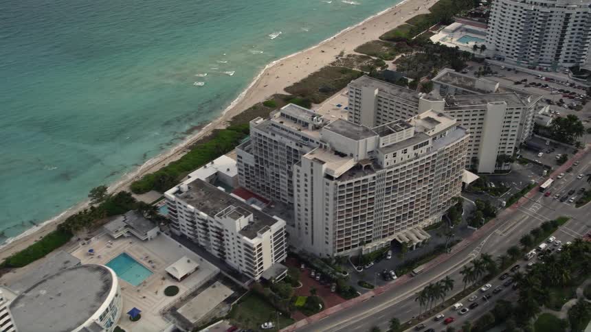 An aerial view of stunning condominium buildings located beside the sunny shoreline of Miami Beach Florida