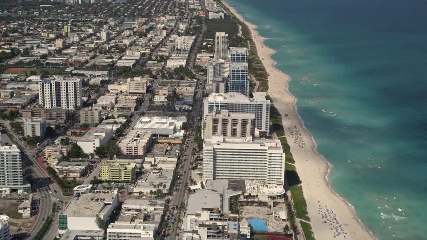 A wide-angle aerial view of Miami Beachs beachfront condominium skyscraper and neighboring hotels offering a breathtaking perspective of the seaside recreational activities enjoyed in this bustling metropolis