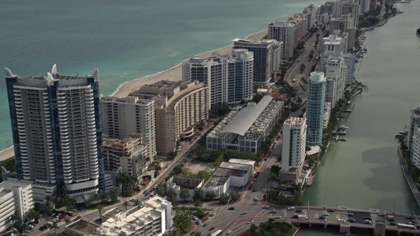 Aerial view of Indian Creek Drive tilting up to reveal a row of oceanfront condominiums in Miami Beach Florida