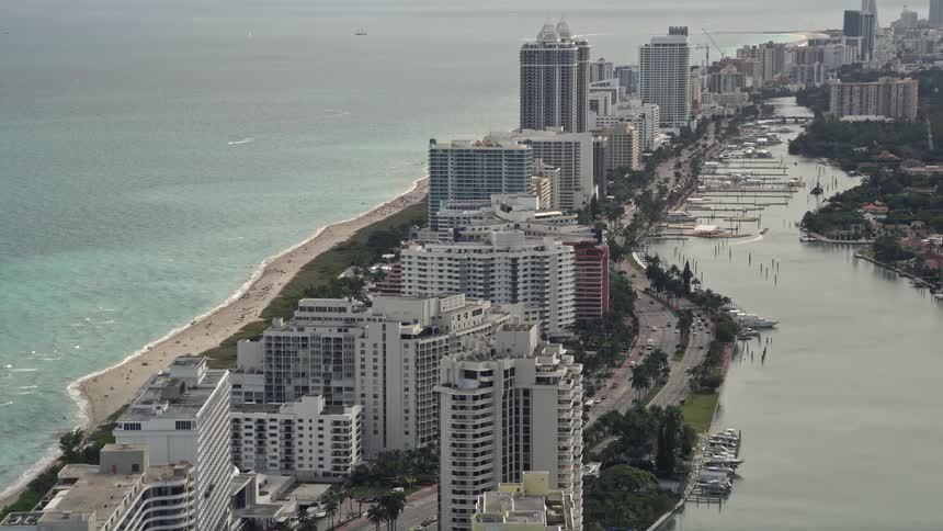 Aerial footage of beachfront condominiums on Collins Avenue in Miami Beach Florida that reveals the shoreline and coastline of the area
