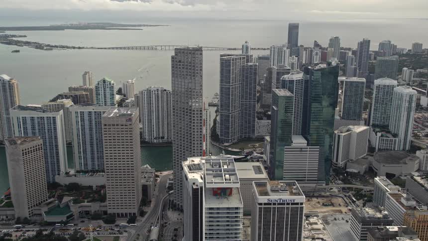 Aerial flyover of Bayfront Park and Southeast Financial Center in Downtown Miami Florida with yachts docked nearby on an overcast day