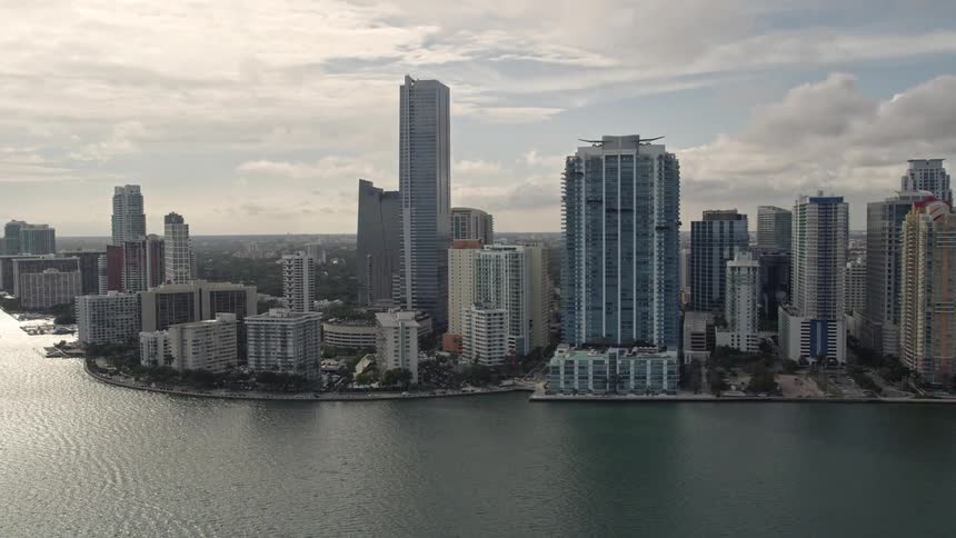 This is an aerial view of Downtown Miami Floridas bayfront area showcasing the towering high-rise buildings hotels and residential buildings on the coastline