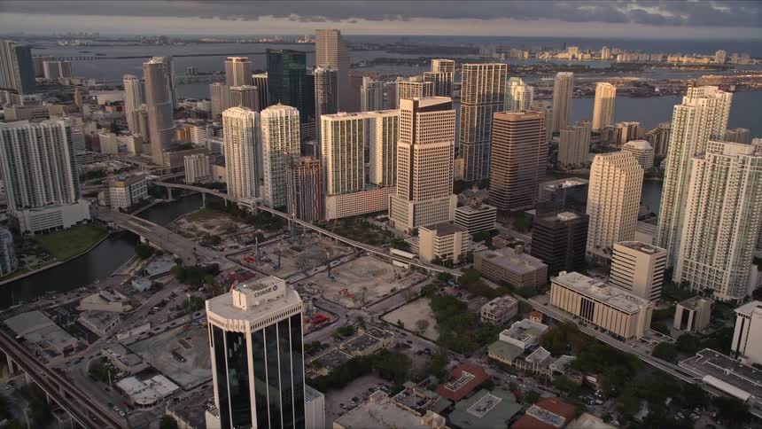 An aerial view of Downtown Miamis skyscrapers at dusk with cloudy skies and an approaching shot