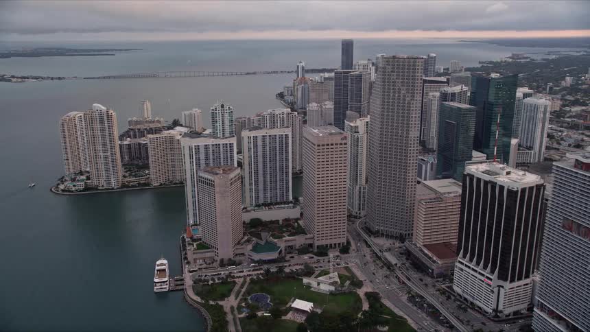 This aerial footage captures the stunning skyline of downtown Miami surrounded by Bayfront Park and the coastline at sunset