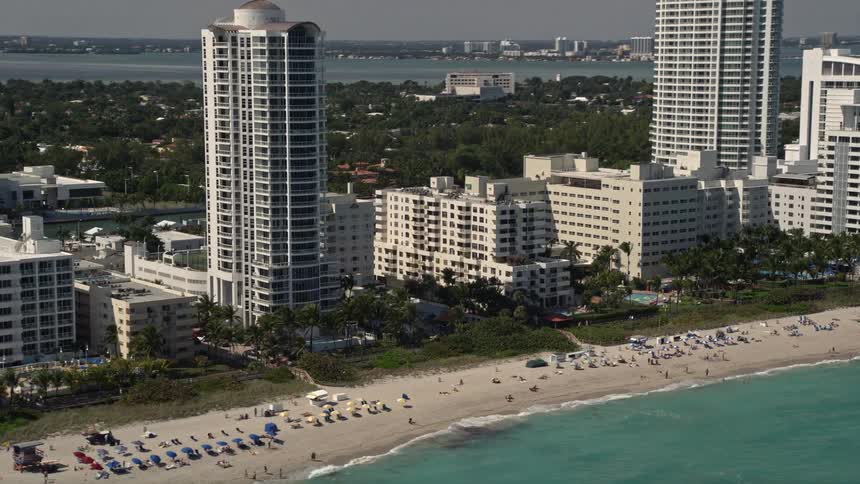 Aerial footage of Miami Beach Florida showing beachfront hotels and sunbathers enjoying the coastline and the ocean