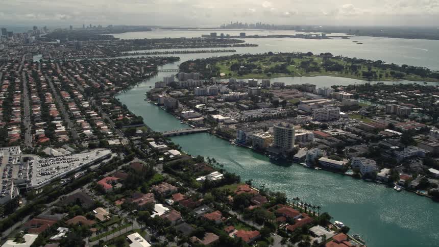 A stunning aerial pan over the seaside neighborhoods of Bal Harbour and Surfside Florida showcasing the luxurious waterfront residences