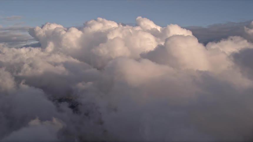 Approaching a thick bank of clouds over Miami during sunset in Florida with the sun shining brightly upon cumulus clouds floating across the sky