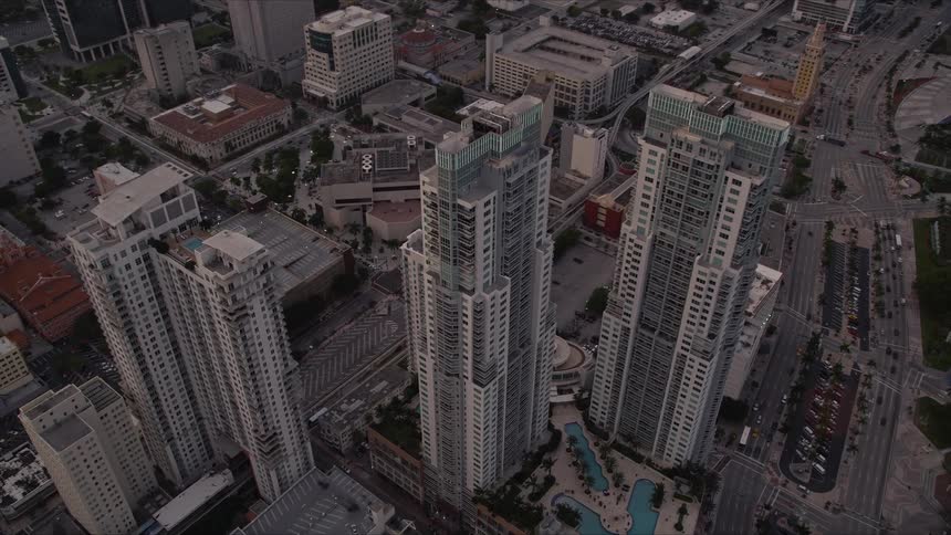 Aerial footage of the Vizcayne towers in Downtown Miami at sunset with a view of heavy traffic passing through the metropolis