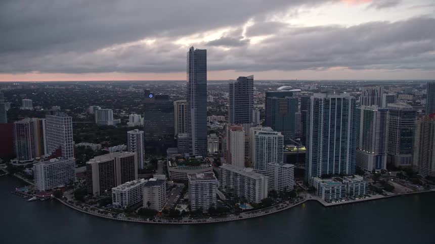 A breathtaking aerial flyby of high-rise hotels and skyscrapers on the waterfront at sunset in downtown Miami Florida