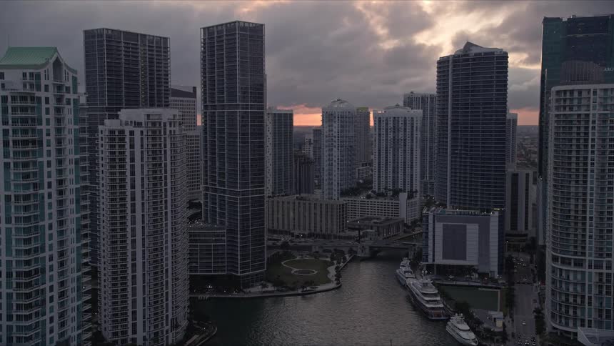 A breathtaking aerial view of Miamis downtown metropolis at dusk approaching Icon Brickell and Brickell on the River surrounded by the stunning Miami River all captured in Floridas spring or summer season