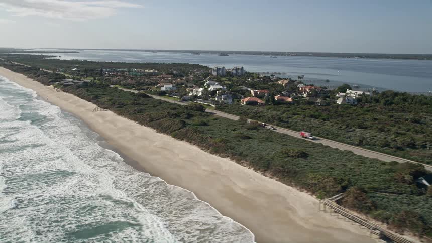 Aerial flyby of homes and a motel by the beach in Melbourne Beach Florida with a clear view of the coastline recreational activities tourism and residential areas