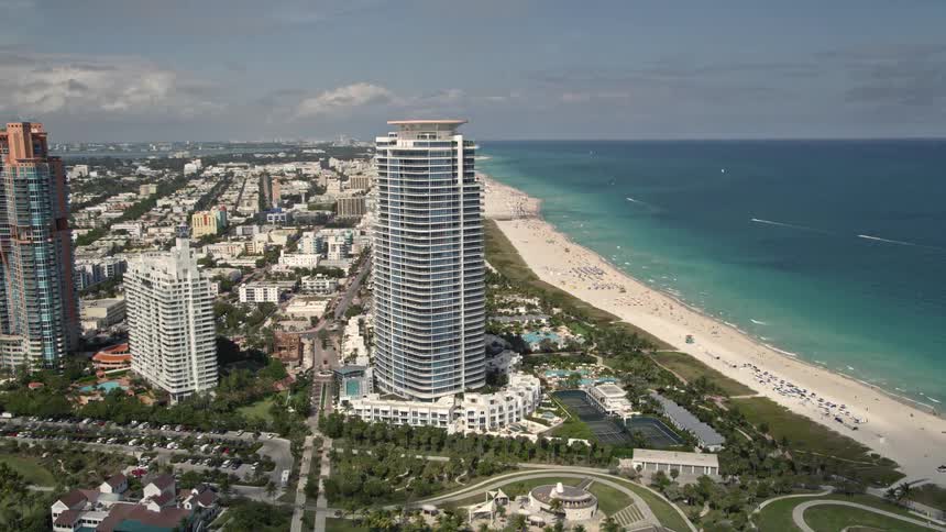 Orbiting above South Beachs modern beachfront skyscrapers tourists and sunbathers can be seen enjoying the recreation and entertainment on the white sand shorelines