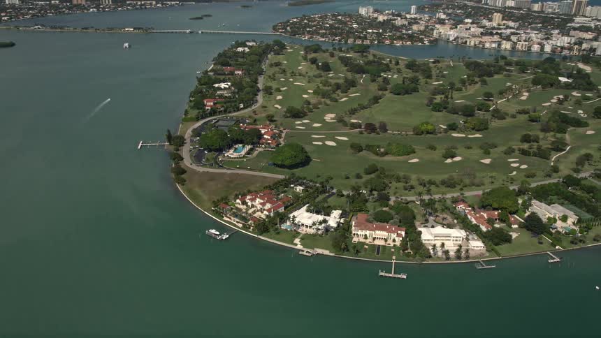 Aerial footage of luxurious waterfront mansions and golf course on Indian Creek Island in Florida