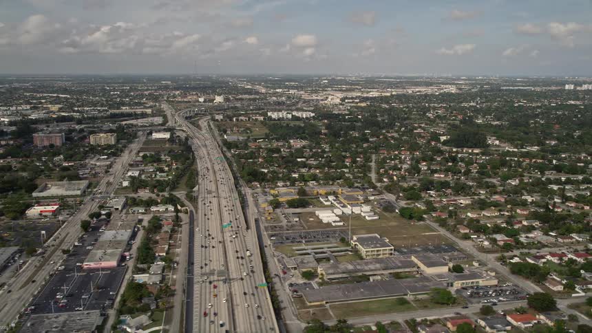 Aerial view of a busy freeway cutting through residential neighborhoods in Golden Glades Florida on a partly cloudy day